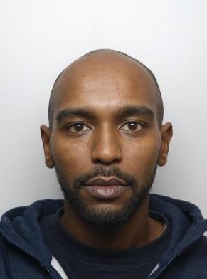 A Black man with a bald head, a black, short moustache and beard