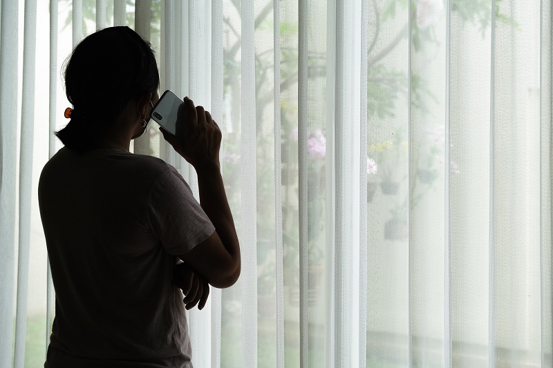 A silhouette of a woman on the phone looking out of the window and making a telephone call