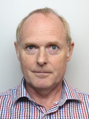 Christopher Cave looking into the camera wearing a stripey shirt