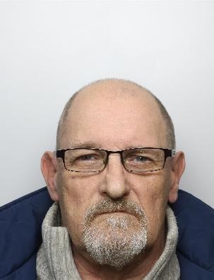 mugshot of a man with a white beard and wearing a dark coat