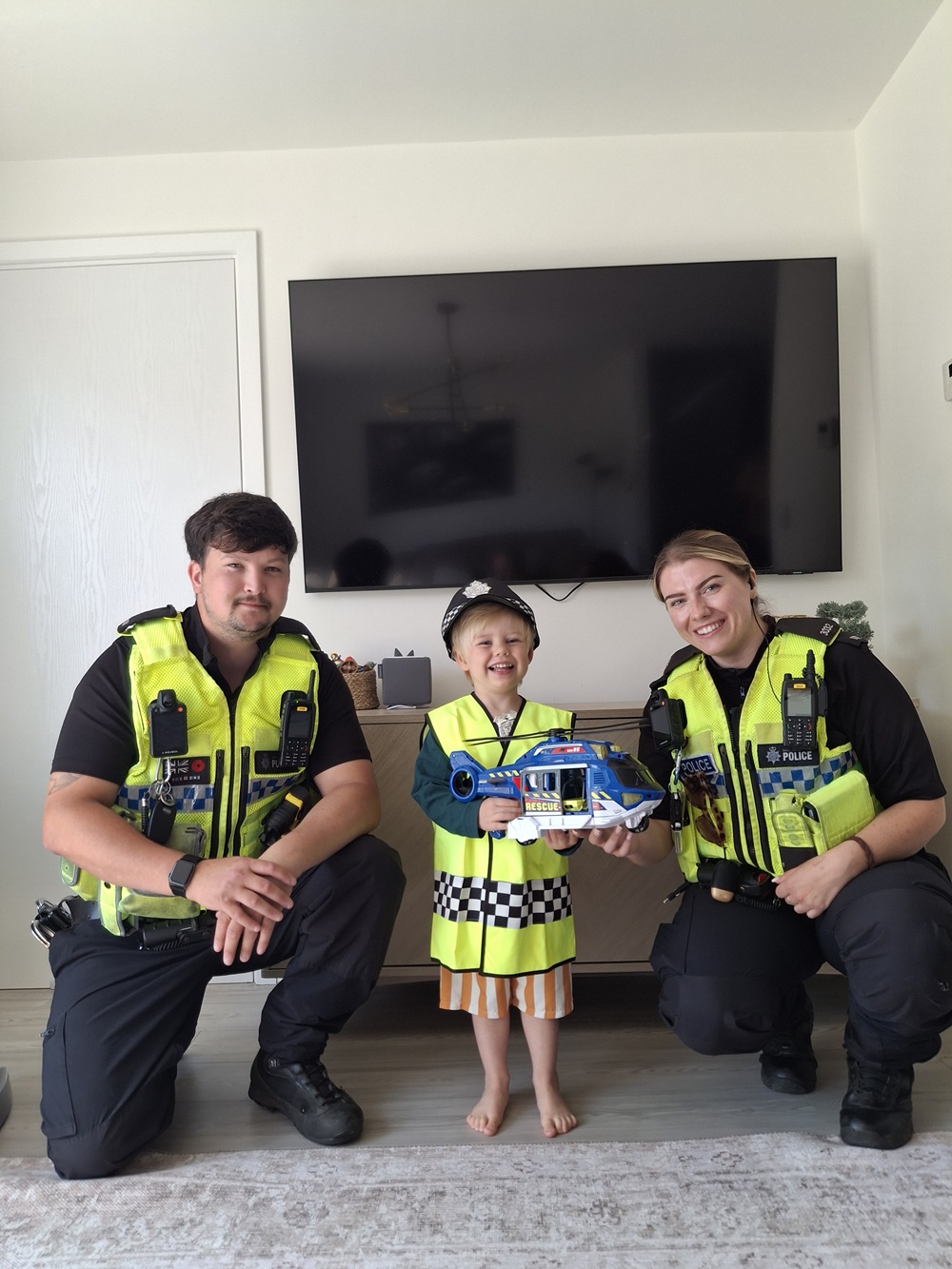 Two police officers kneel as they pose for a picture alongside little boy James