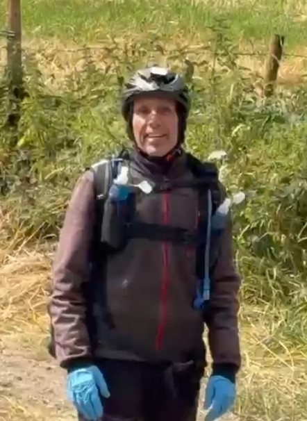 A white man wearing a bike helmet and blue gloves