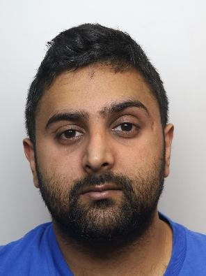 Haranand Rai is an Asian man with black hair, facial hair and wearing a blue t-shirt. He is standing in front of a white background for a custody picture