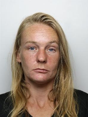 Katie Hudson is a white woman with blonde hair and wearing a black top. She is standing in front of a white background for a custody picture