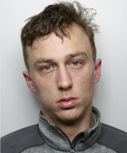 Tommy Knott is a white man with short brown hair and wearing a grey jacket. He is standing in front of a white background for a custody picture
