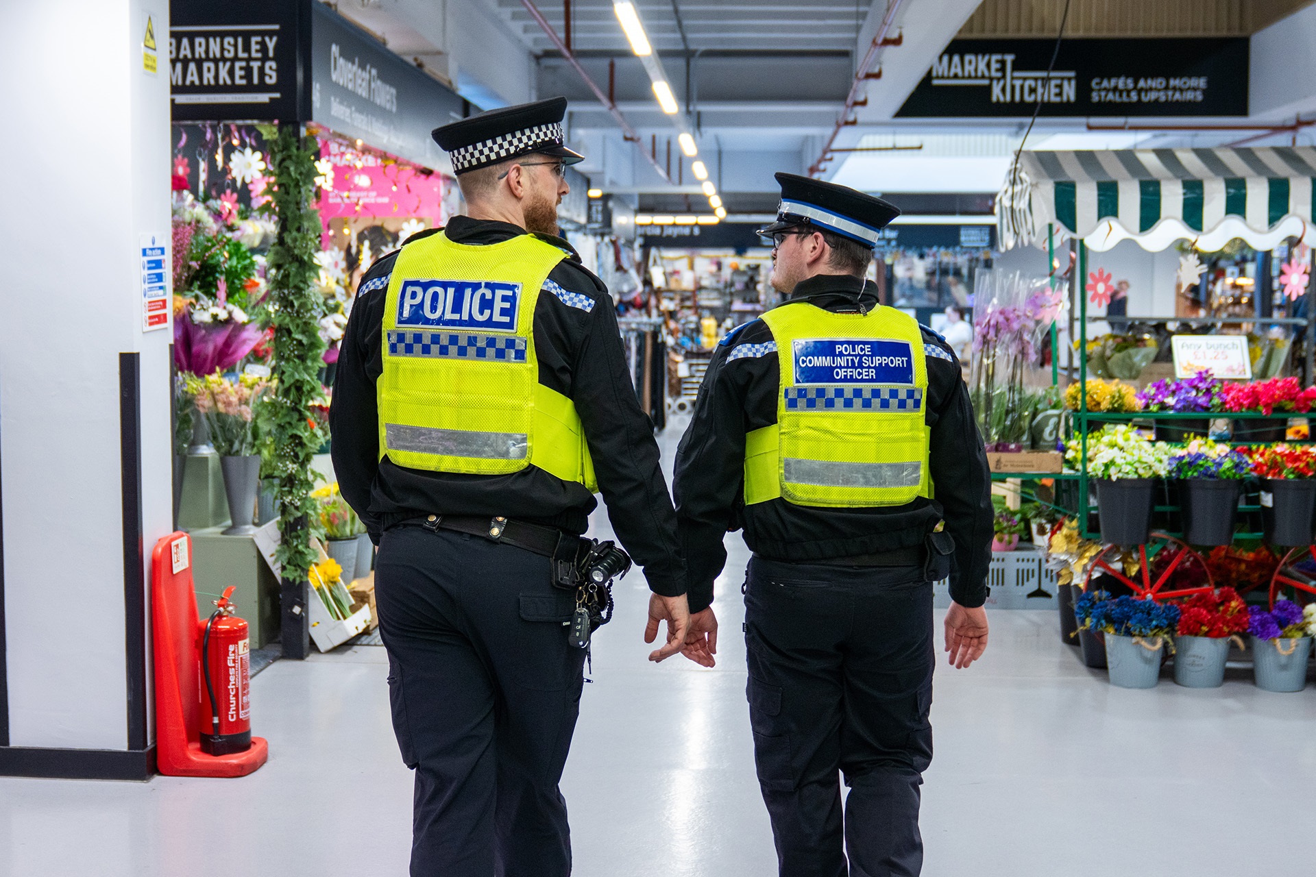Two uniformed officers walking through a market hall