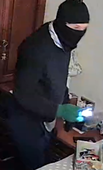 CCTV image of man wearing a black balaclava, black jacket and green gloves