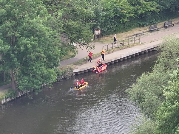 A aerial view of a river with officers searching waters 