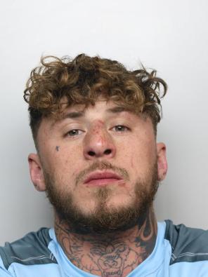 A mug shot of a man with curly hair and wearing a blue tshirt