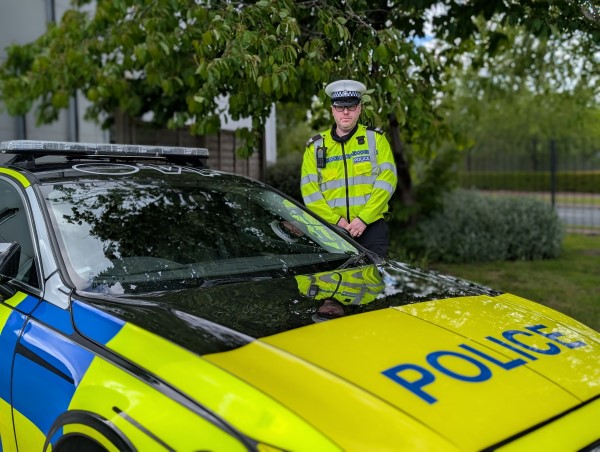 A police officer in reflective clothing standing next to a police car