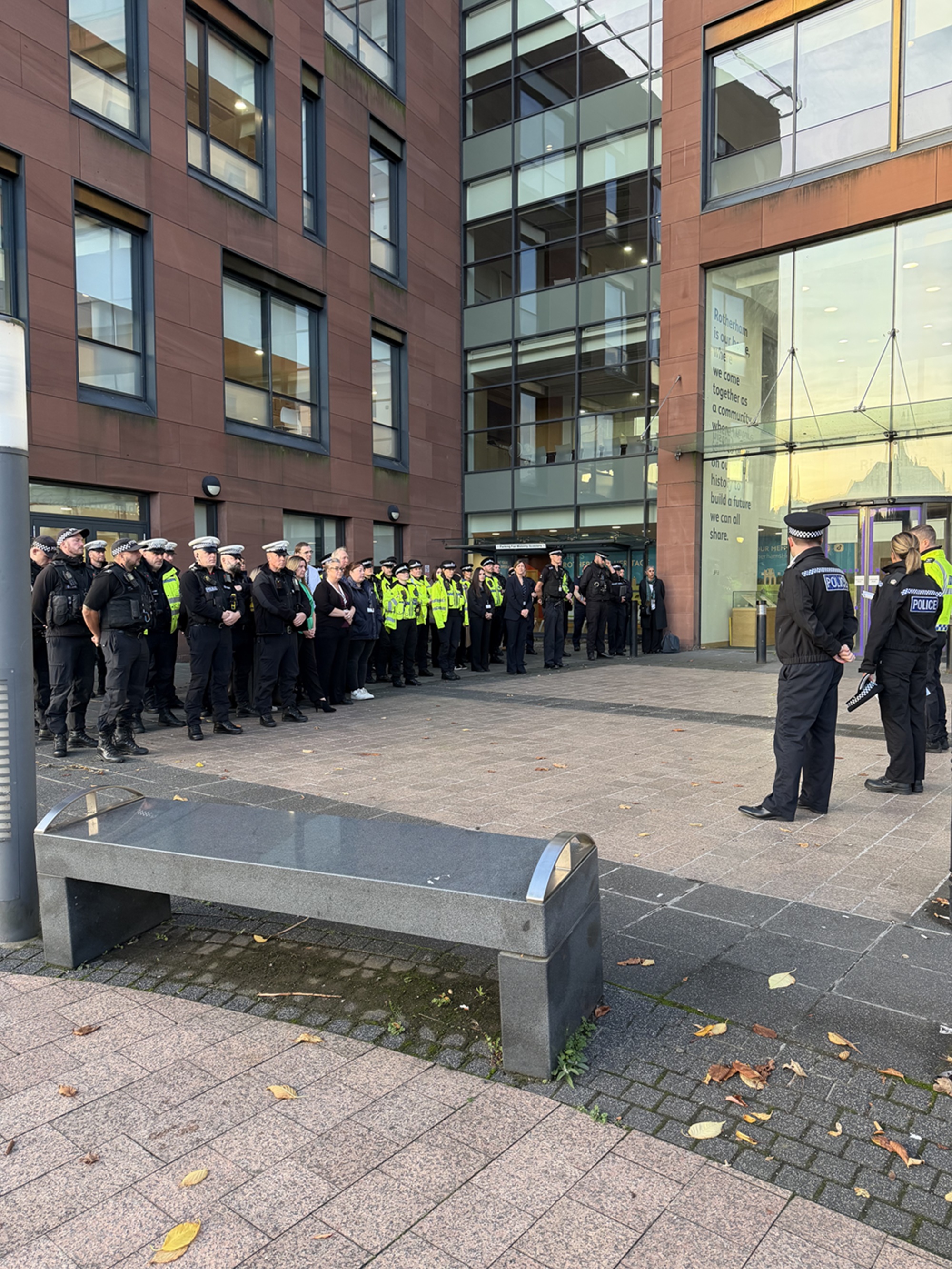 A group of police officers stood together being briefed outside a building by three other officers