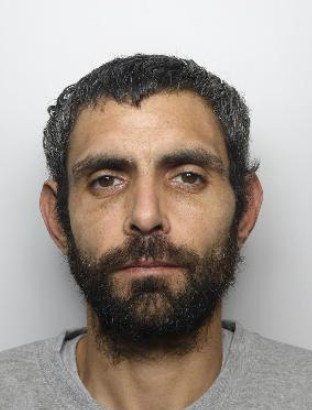A mugshot of a man with dark hair 