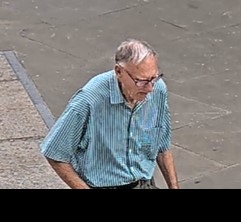 A white elderly man with short grey hair wearing glasses and a blue stripey shirt
