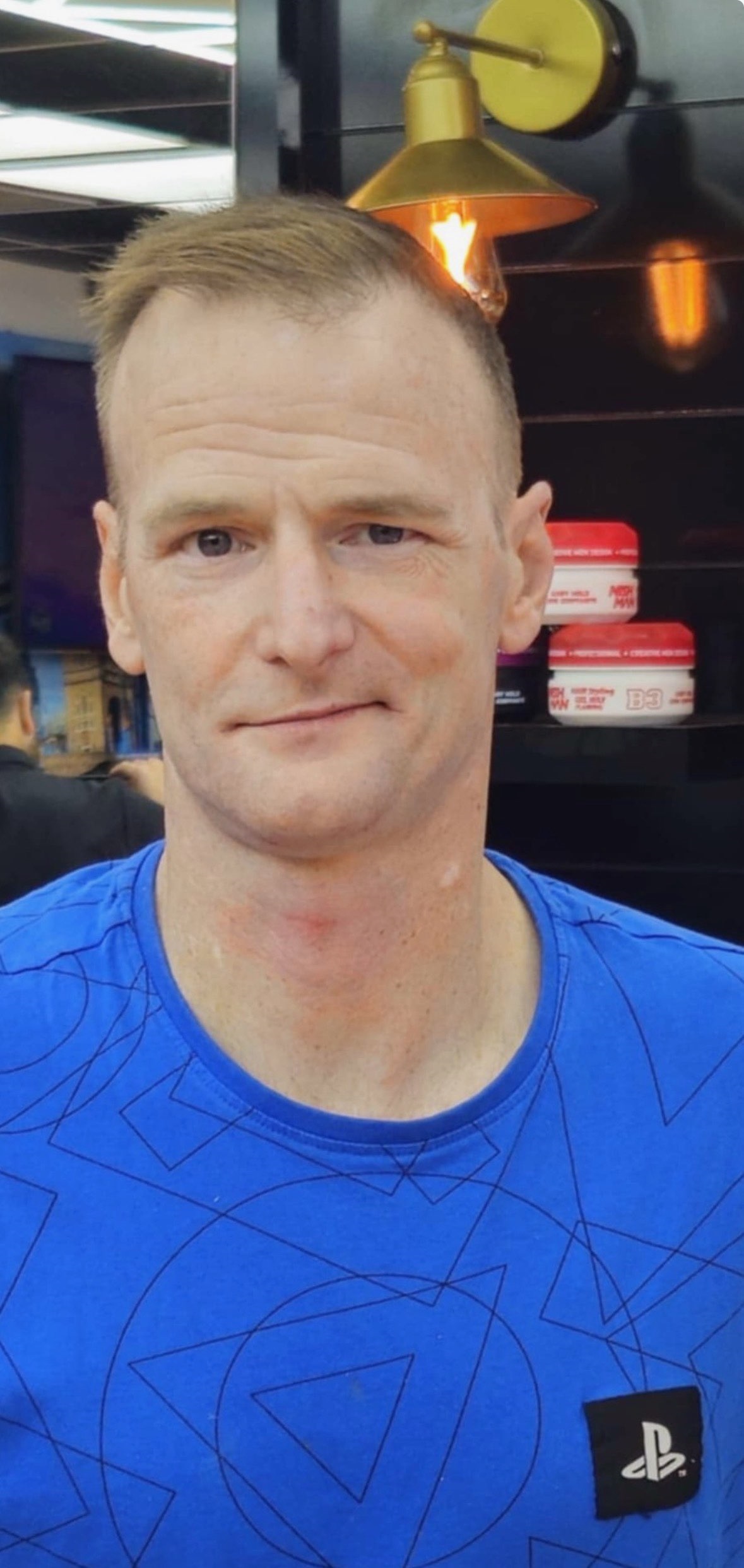 A man with short light hair wearing a blue t-shirt